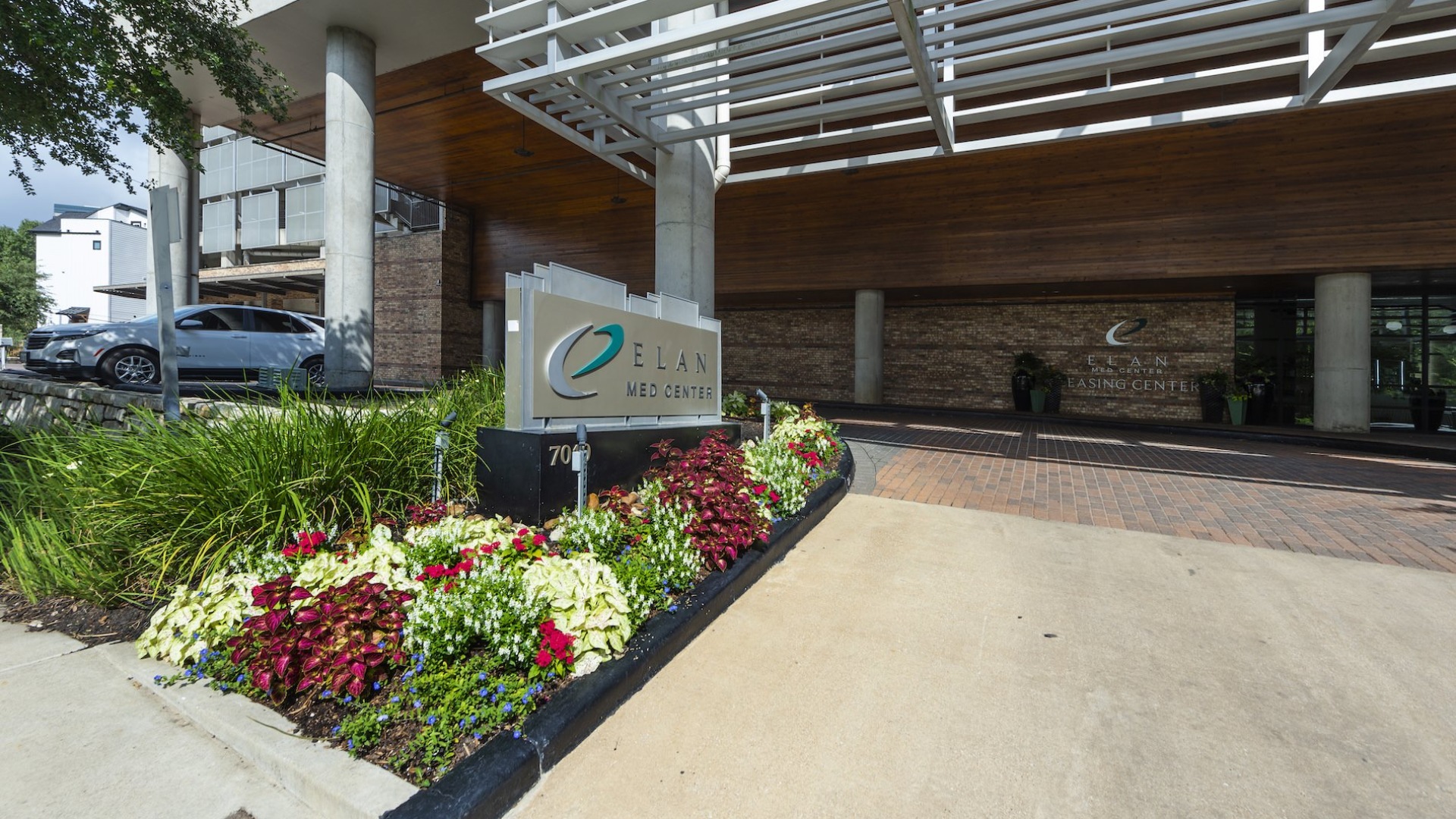a sign in a flower bed outside a building