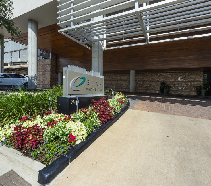 a sign in a flower bed outside a building